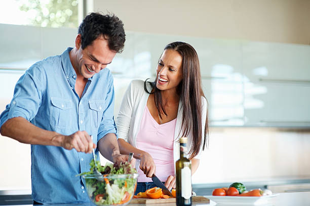 Thanks for helping Happy man assisting woman in preparing salad in the kitchen mid adult couple stock pictures, royalty-free photos & images