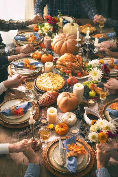 Thanksgiving celebration traditional dinner concept Group of friends or family members giving thanks to God at festive turkey dinner table together. Thanksgiving celebration traditional dinner concept banquet photos stock pictures, royalty-free photos & images