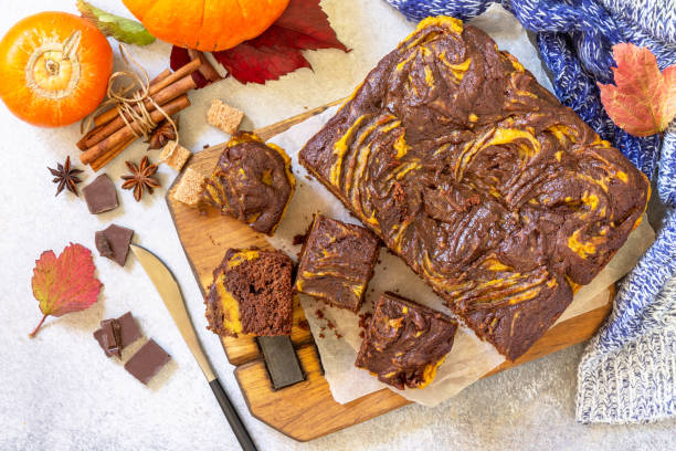 Thanksgiving Day homemade baking. Chocolate brownie pumpkin puree cake dessert with spices on a stone table. Top view flat lay background. stock photo
