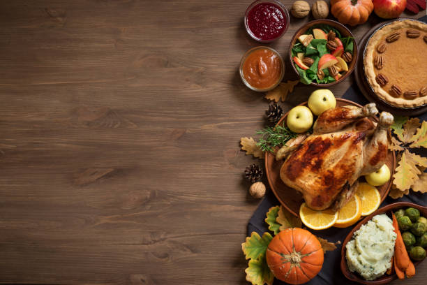 Thanksgiving Dinner background Thanksgiving dinner background with turkey and all sides dishes, pumpkin pie, fall leaves and seasonal autumnal decor on wooden background, top view, copy space. thanksgiving food stock pictures, royalty-free photos & images