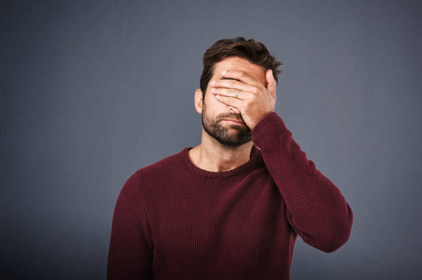 That was such a flop Studio shot of a young man covering his eyes in regret against a gray background guilt stock pictures, royalty-free photos & images