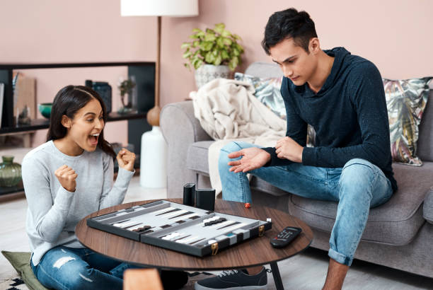 The backgammon queen of self quarantine! Shot of a young couple playing a game of chess at home backgammon stock pictures, royalty-free photos & images
