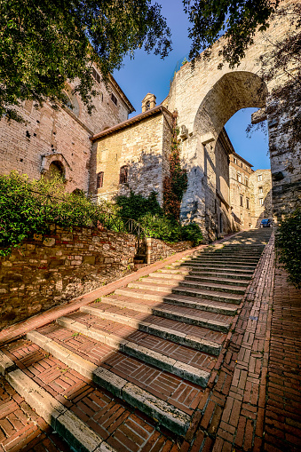 The beautiful staircase leading to Porta Trasimena (Trasimena Gate) in the medieval heart of Perugia, in Umbria, central Italy. One of the seven gates of the Etruscan walls of Perugia, rebuilt in the Middle Ages with the current ogival arch. Founded by the Etruscans on an ancient Umbrian settlement, Perugia is one of the most loved and visited medieval Italian cities, rich in artistic and architectural treasures that span almost three thousand years of history. The Umbria region, considered the green lung of Italy for its wooded mountains, is characterized by a perfect integration between nature and the presence of man, in a context of environmental sustainability and healthy life. In addition to its immense artistic and historical heritage, Umbria is famous for its food and wine production and for the quality of the olive oil produced in these lands. Super wide angle image in high definition format.
