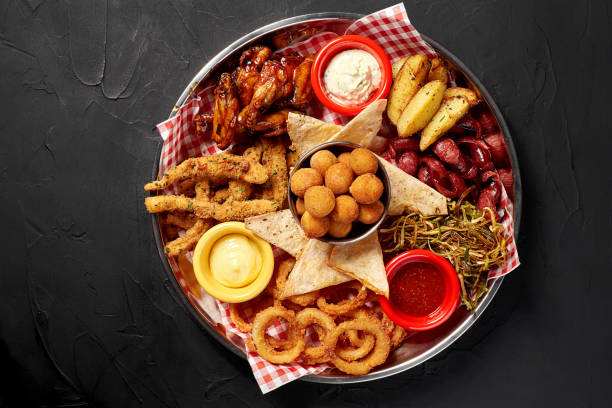 The beer plate with spicy chicken wings, calamari rings, fries onion rings, cheese balls, breaded, tartar sauce and garlic The beer plate with spicy chicken wings, calamari rings, fries onion rings, cheese balls, breaded, tartar sauce and garlic. Food and beverages concept. Still life. Copy space. Flat lay appetizer stock pictures, royalty-free photos & images