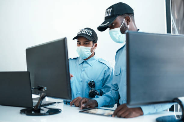 The best security detail for your business Shot of two masked young security guards on duty at the front desk of an office defending activity stock pictures, royalty-free photos & images