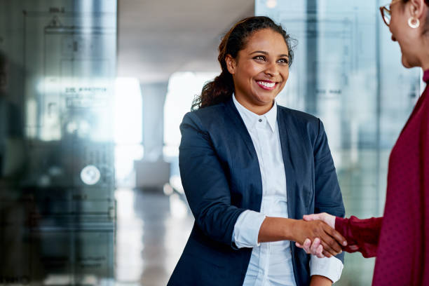 The best way to success is through your network Shot of two businesswomen shaking hands in a modern office business relationship stock pictures, royalty-free photos & images