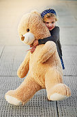 Portrait of a cute little girl holding an enormous teddybear while playing outside