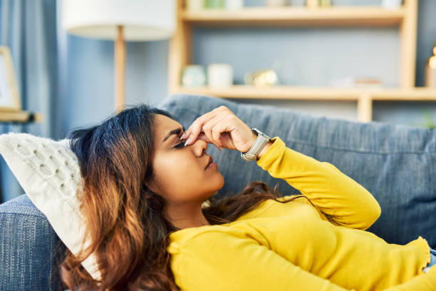 The boredom is giving me a headache Shot of a young woman experiencing a bad headache while relaxing at home headache stock pictures, royalty-free photos & images