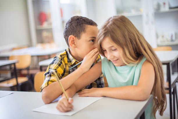 The boy whispers to the girl the answers. stock photo
