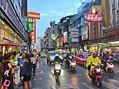 Bangkok/Thailand. 08/19/2017. Mopeds, taxis and cars driving at dusk on the streets of Bangkok's Chinatown.