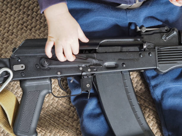the child is playing with a weapon. a machine gun in the hands of a little boy stock photo