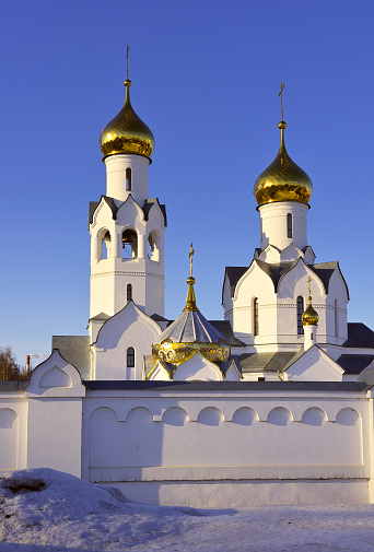 The towers of the Orthodox church in the Old Russian architectural traditions with golden domes and crosses against the blue sky. Siberia, Russia
