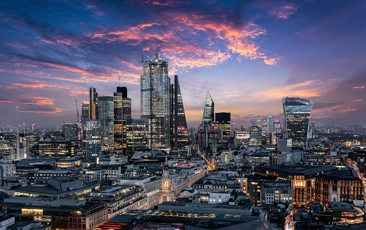 The City of London, financial district of the Metropole, just after sunset with illuminated buildings and cloudy sky, United Kingdom