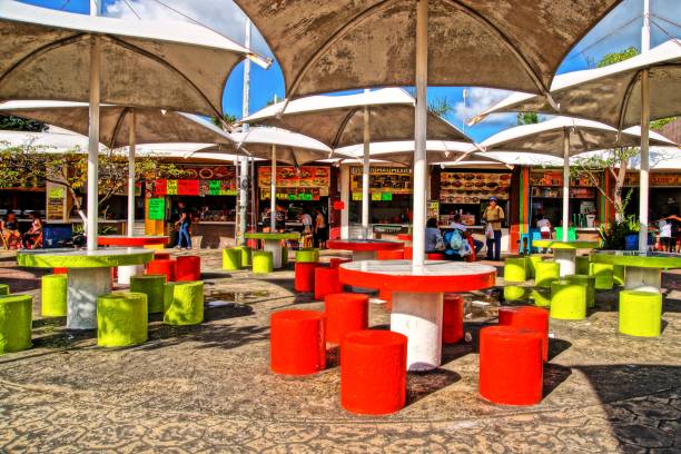 The colorful fast food restaurants of Palapas Square in Cancùn (Mexico) 11/07/2016 - Cancùn, Mexico Cancùn is not only a seaside resort or spring break destination for young foreign tourists. For a more traditional and genuine overview of the local way of life, visitors should explore the city itself and its districts. Trying local food is also a good way of discovering the culture. Palapas Square is one of those popular places in town where families gather in the evening, enjoy cheap yet tasty food, while listening to live music. mexique stock pictures, royalty-free photos & images