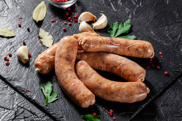 The concept of farm, organic products. Raw homemade pork barbecue sausages on a black slate board. background image. copy space stock photo