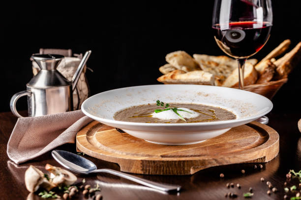 The concept of Italian cuisine. Mushroom soup mashed mushrooms with cream and spices, with olive oil. Next to the table is a glass of red wine. Beautiful serving dishes in the restaurant. stock photo