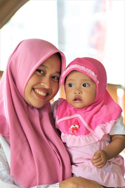 The concept of love for mother and child when playing Mother and child wearing hijab are relaxing at the cafe. The concept of love for mother and child while playing indonesian girl stock pictures, royalty-free photos & images