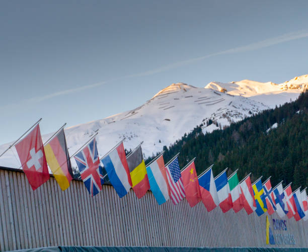 the congress center in Davos with flags of nations at sunrise during the WEF World Economic Forum Davos, GR / Switzerland - 15 January 2020: the congress center in Davos with flags of nations at sunrise during the WEF World Economic Forum alpine climate stock pictures, royalty-free photos & images