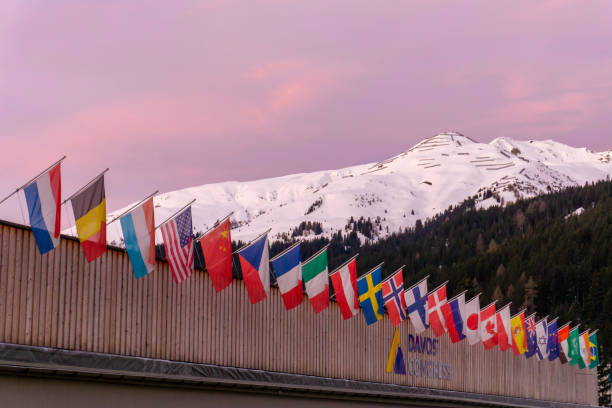 o centro de congressos em davos com bandeiras das nações no nascer do sol durante o fórum econômico do mundo de wef - davos - fotografias e filmes do acervo