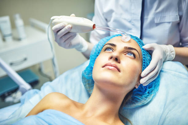 The cosmetologist is caring for the patient's face stock photo