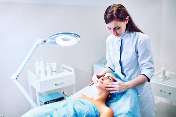 The cosmetologist is caring for the patient's face stock photo