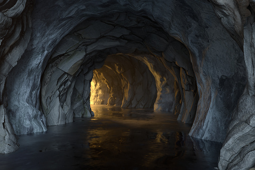 dark entry into underground freshwater cave, with light source, stalactites, and blue water