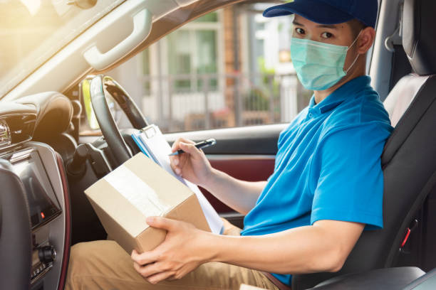 The delivery man is checking the parcel to be delivered on the car. stock photo