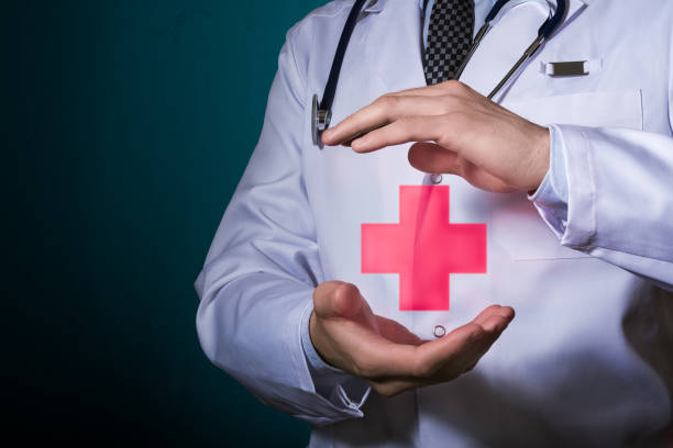 The doctor holds a pictogram of a red cross in his hands. stock photo