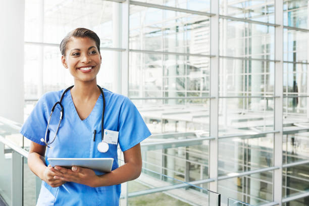 The doctor is in Portrait of a confident young doctor holding a digital tablet in a modern hospital looking away stock pictures, royalty-free photos & images