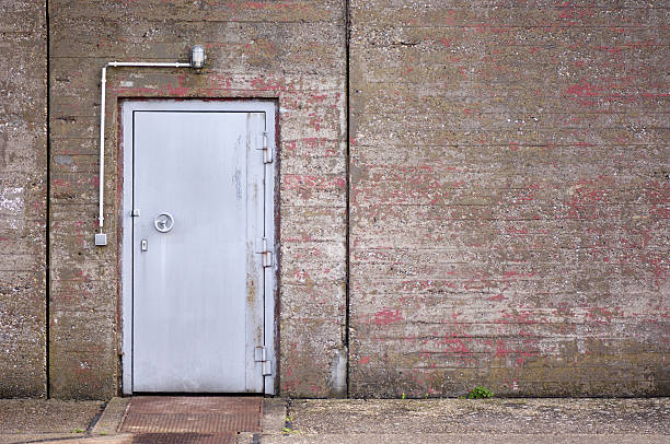 The door Steel door in a rough concrete wall. bomb shelter stock pictures, royalty-free photos & images