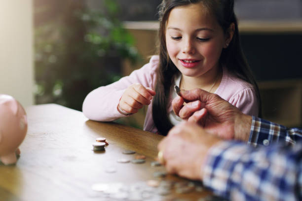 The earlier the better Shot of a little girl learning about money from her grandfather allowance stock pictures, royalty-free photos & images