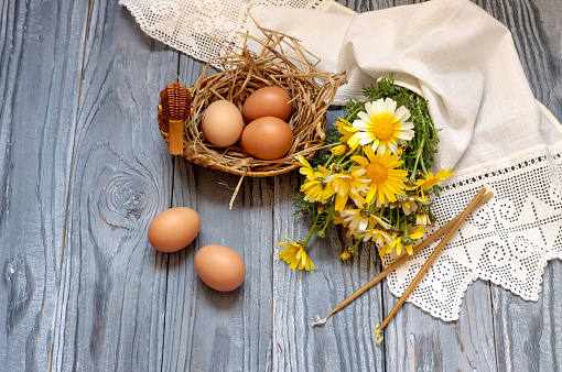 Easter still life. Yellow daisies, candles and eggs on a wooden table close-up.