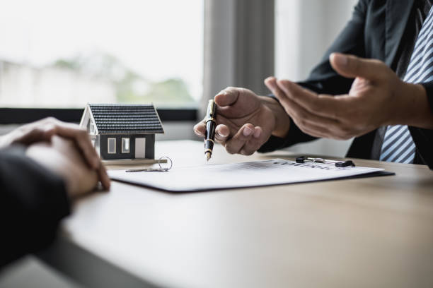 The employee is explaining the rent details and calculating the monthly rent to the tenant before signing the contract. The concept of renting a house. stock photo