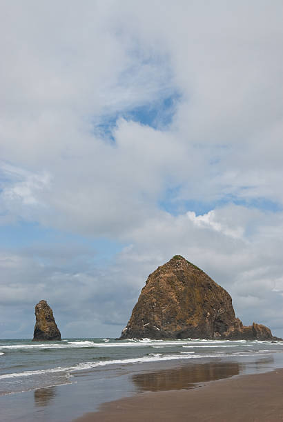Haystack Rock The famous Haystack Rock and nearby Needles are basalt monoliths formed some 15-16 million years ago by lava flows emanating from the Blue Mountains and Columbia Basin. Haystack Rock is also one of the most identifiable rock formations on the Pacific Coast. Haystack Rock and the Needles are in Cannon Beach, Oregon, USA. jeff goulden reflection stock pictures, royalty-free photos & images