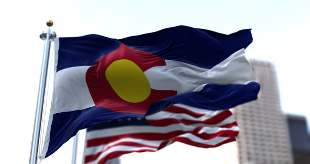 the flag of the US state of Colorado waving in the wind with the American stars and stripes flag blurred in the background stock photo