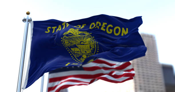 The flags of the Oregon state and United States waving in the wind stock photo