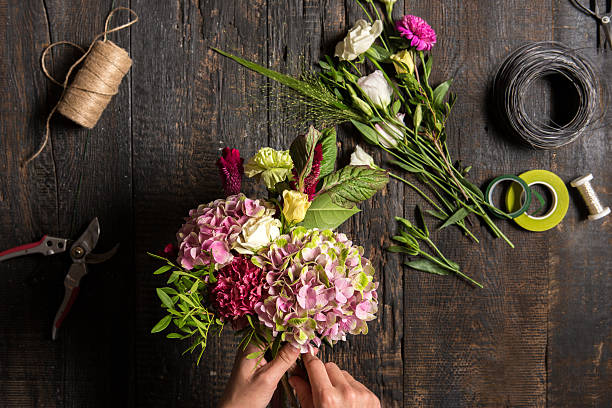 The florist desktop with working tools and ribbons The hands of florist against desktop with working tools and ribbons on wooden background flower arrangement stock pictures, royalty-free photos & images