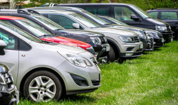 The front part of a series of cars in a parking lot on a grass field stock photo
