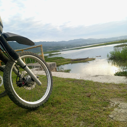 the front wheel of a motorcycle with a lake in the background.