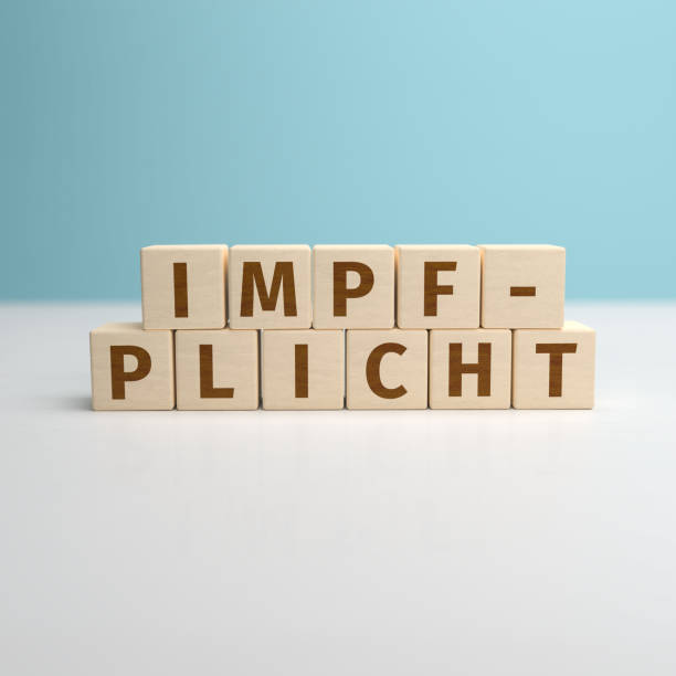 la palabra alemana impfpflicht (vacunación obligatoria) construida a partir de letras en cubos de madera. - vaccine mandate fotografías e imágenes de stock