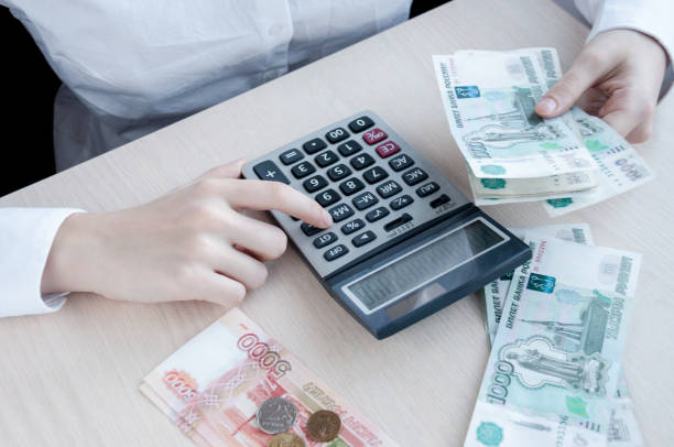 테이블에서 여자는 계산기와 이익 고려 - 러시아 루블 뉴스 사진 이미지