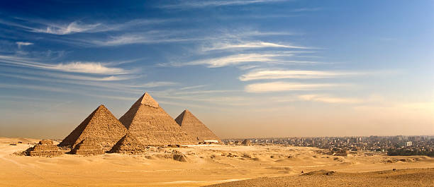 The Giza Plateau skyline Egypt. Cairo - Giza. General view of pyramids and cityscape from the Giza Plateau (on front side: three pyramids popularly known as Queens' Pyramids; next in order from left: the Pyramid of Menkaure /Mykerinos/, Khafre /Chephren/ and Chufu /Cheops/ - known as the Great Pyramid. There is a modern city in background). The Pyramid Fields from Giza to Dahshur is on UNESCO World Heritage List cairo stock pictures, royalty-free photos & images