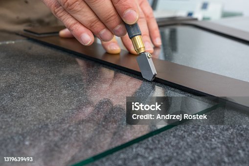 istock The glazier cuts the glass with a hand-held cutting tool. Handicraft plant, Close up 1319639493