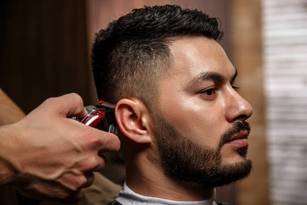 the guy is a dark-haired Asian Indian appearance on a haircut in a barbershop . cinematic image stock photo