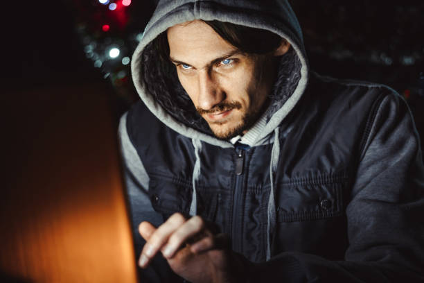 the hacker behind a computer stock photo