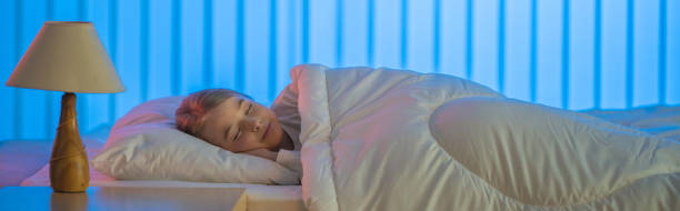 The happy girl sleeping on the bed. Evening night time stock photo