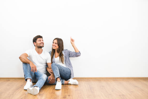 The happy man and woman sit on the background of the white wall stock photo