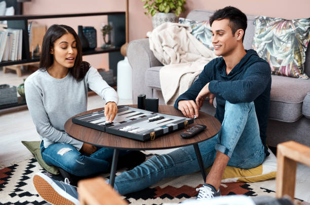 The healthy kind of game playing Shot of a young couple playing a game of backgammon at home backgammon stock pictures, royalty-free photos & images