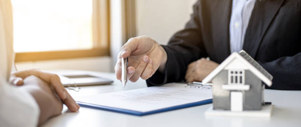 The home salesman and buyer is signing a purchase agreement after discussing the details. stock photo