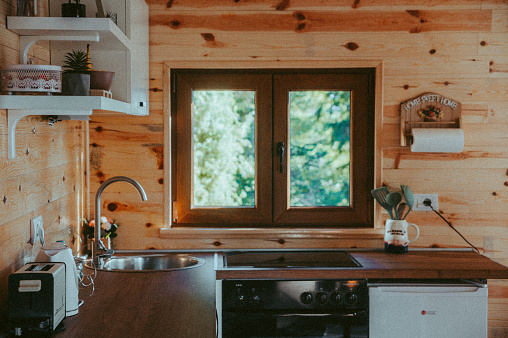 Cute small cottage kitchen design. View of the pine forest through the kitchen window
